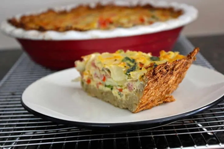 A slice of ham and spinach quiche on a plate.