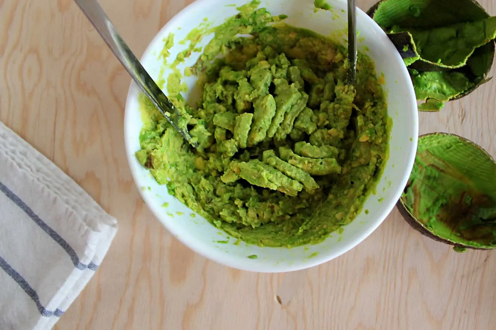 Mashing avocadoes with a potato masher.