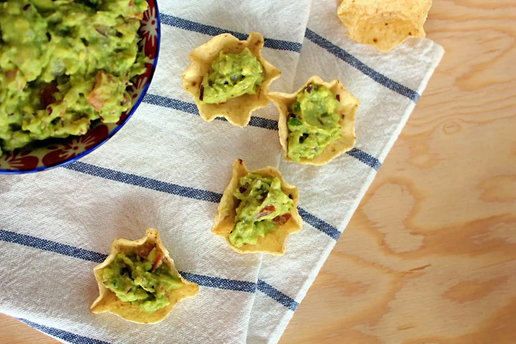 Nacho chips piled high with loaded guacamole.