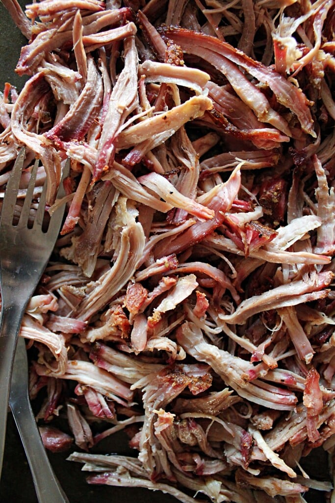 Close up of the smoked pulled pork and two stainless steel forks.
