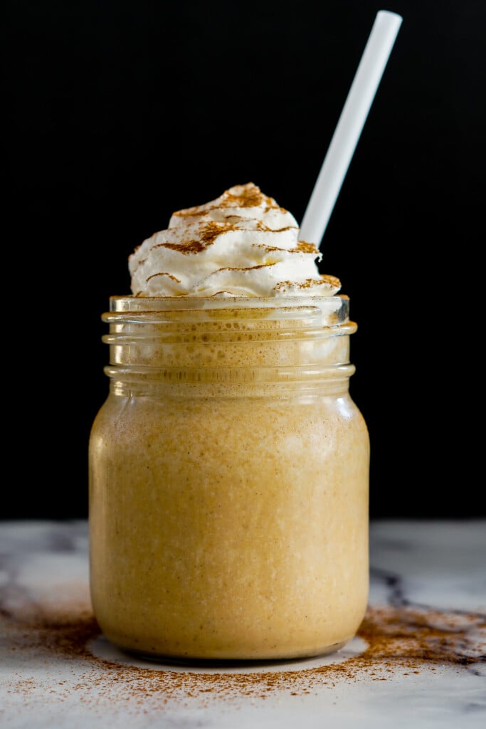 Pumpkin pie milkshake in a vintage jar topped with a generous helping of whipping cream.