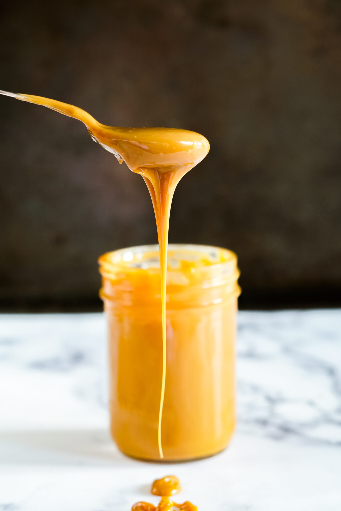 Creamy sous vide dulce de leche dripping off a spoon