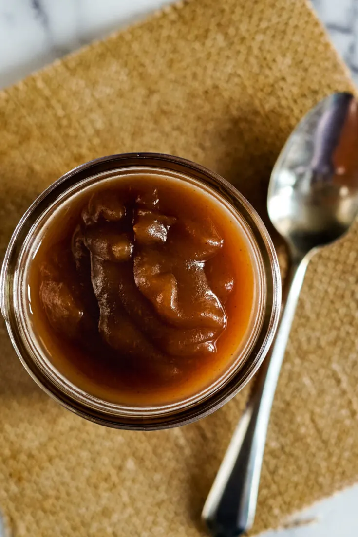 Instant pot apple butter in a small jar with a spoon for spreading.
