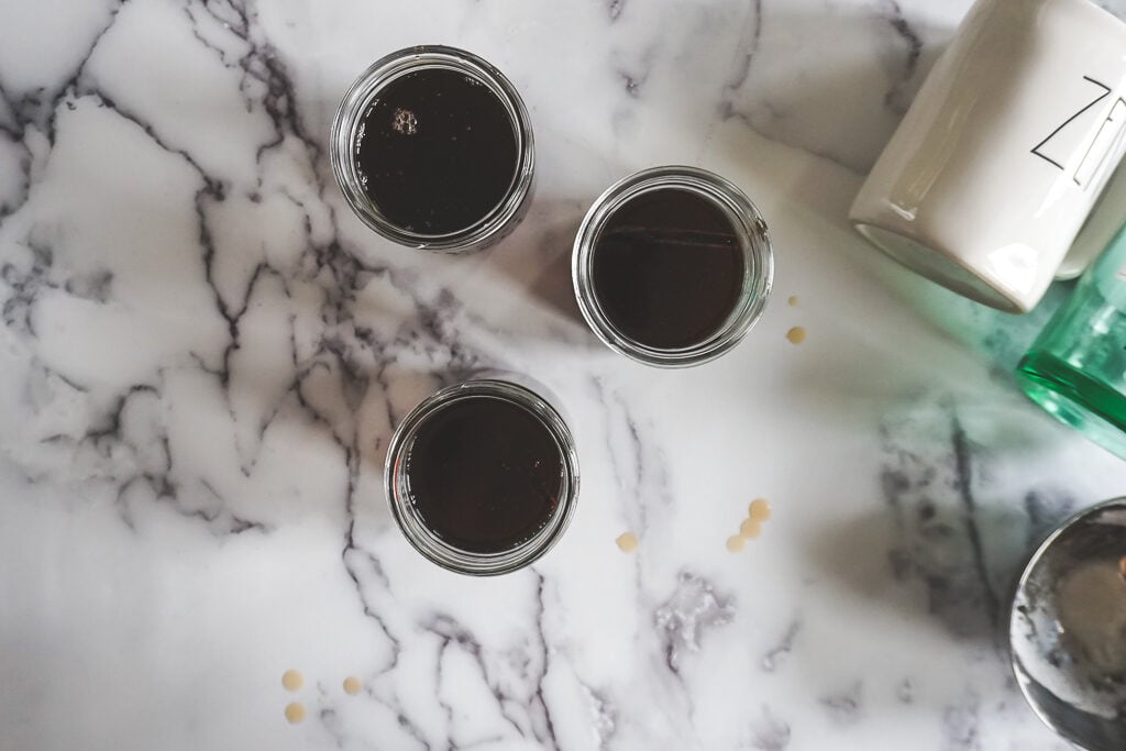 Mixed ingredients poured into jars with drips around the table. 