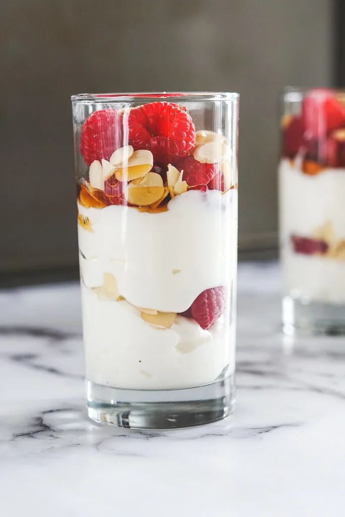 Tall narrow cups with sous vide yogurt, fresh raspberries, sliced almonds layered.