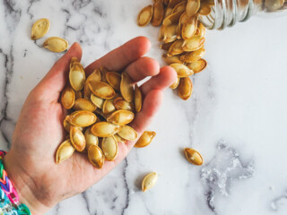 An outstretched hand holding smoked pumpkin seeds