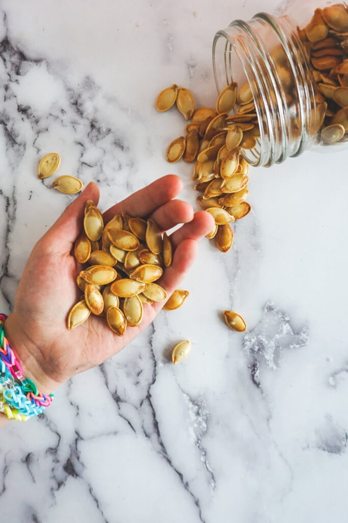 An outstretched hand holding smoked pumpkin seeds