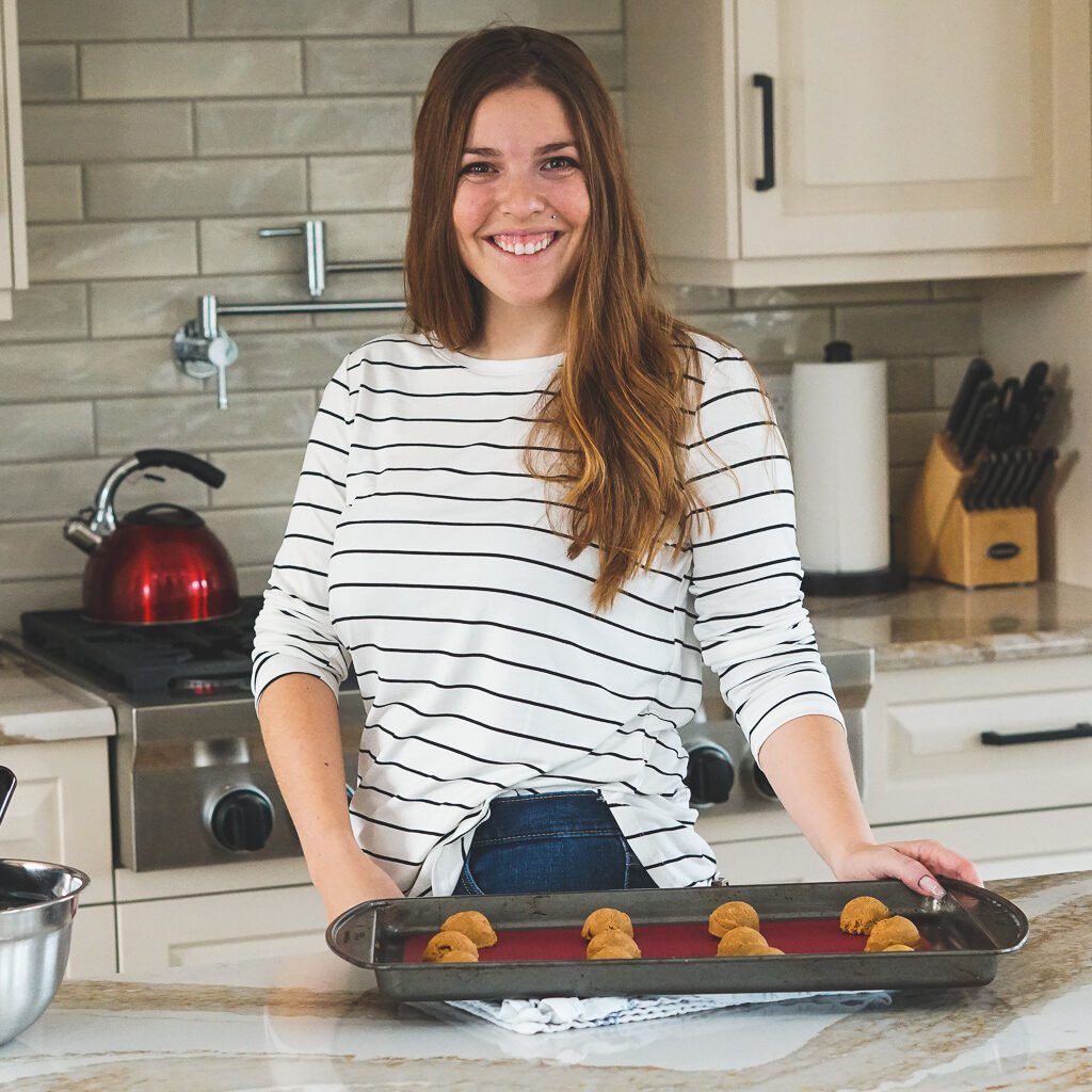 Ally, the creator at crave the good holding a baking sheet with unbaked cookies.
