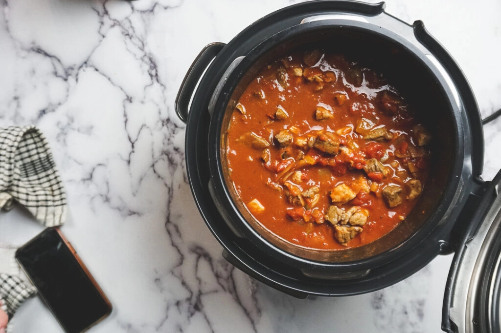 Keto Instant Pot Chili ready to be pressure cooked in the Instant Pot. There's a cellphone in the background.