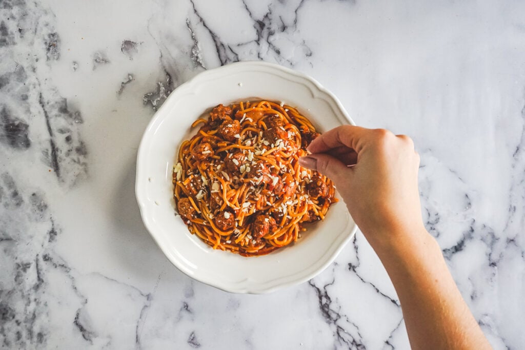 Sprinkling parmesean on the spaghetti. 