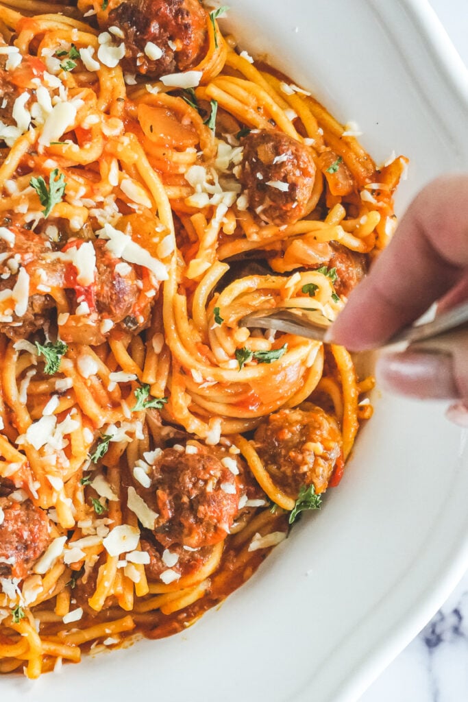 A hand twirling a fork in the instant pot spaghetti and meatballs dish.