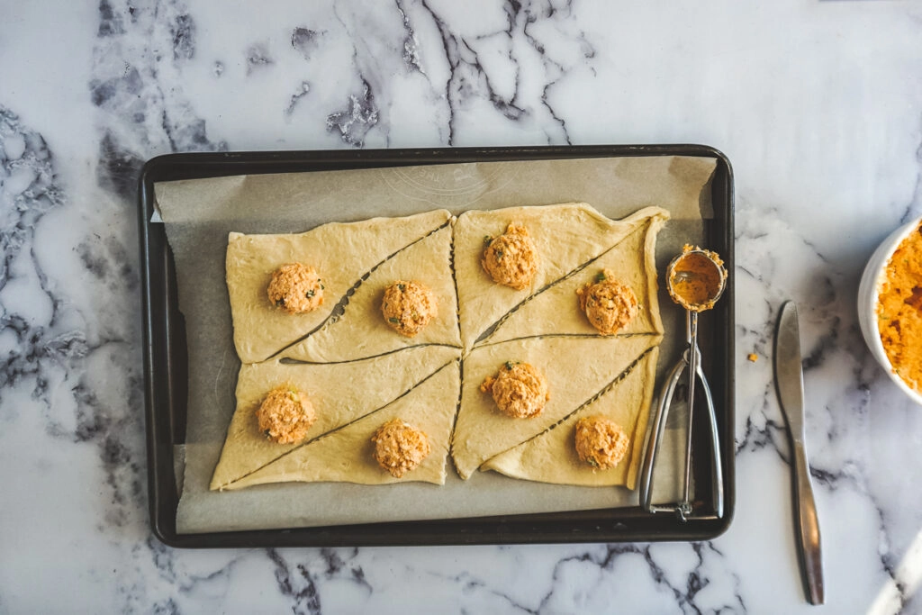 Unrolled crescent rolls with buffalo chicken dip scooped into each one.