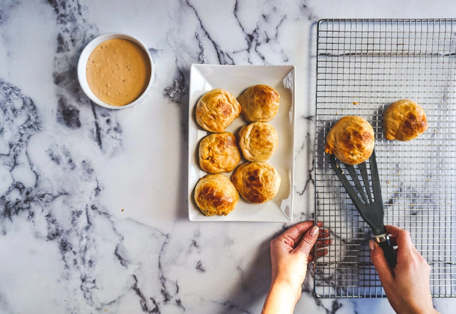 Scooping the buffalo chicken bombs off a cooling rack onto a white serving dish.
