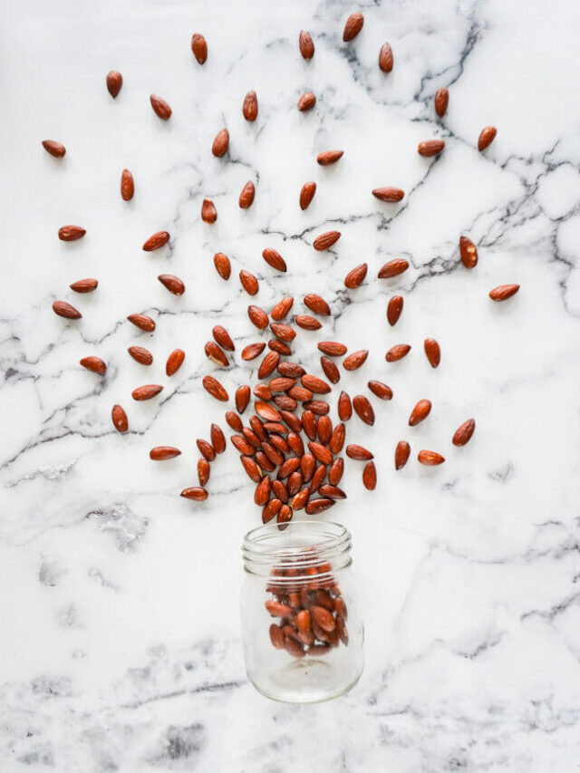 Air fryer roasted almonds spilling out of a jar.