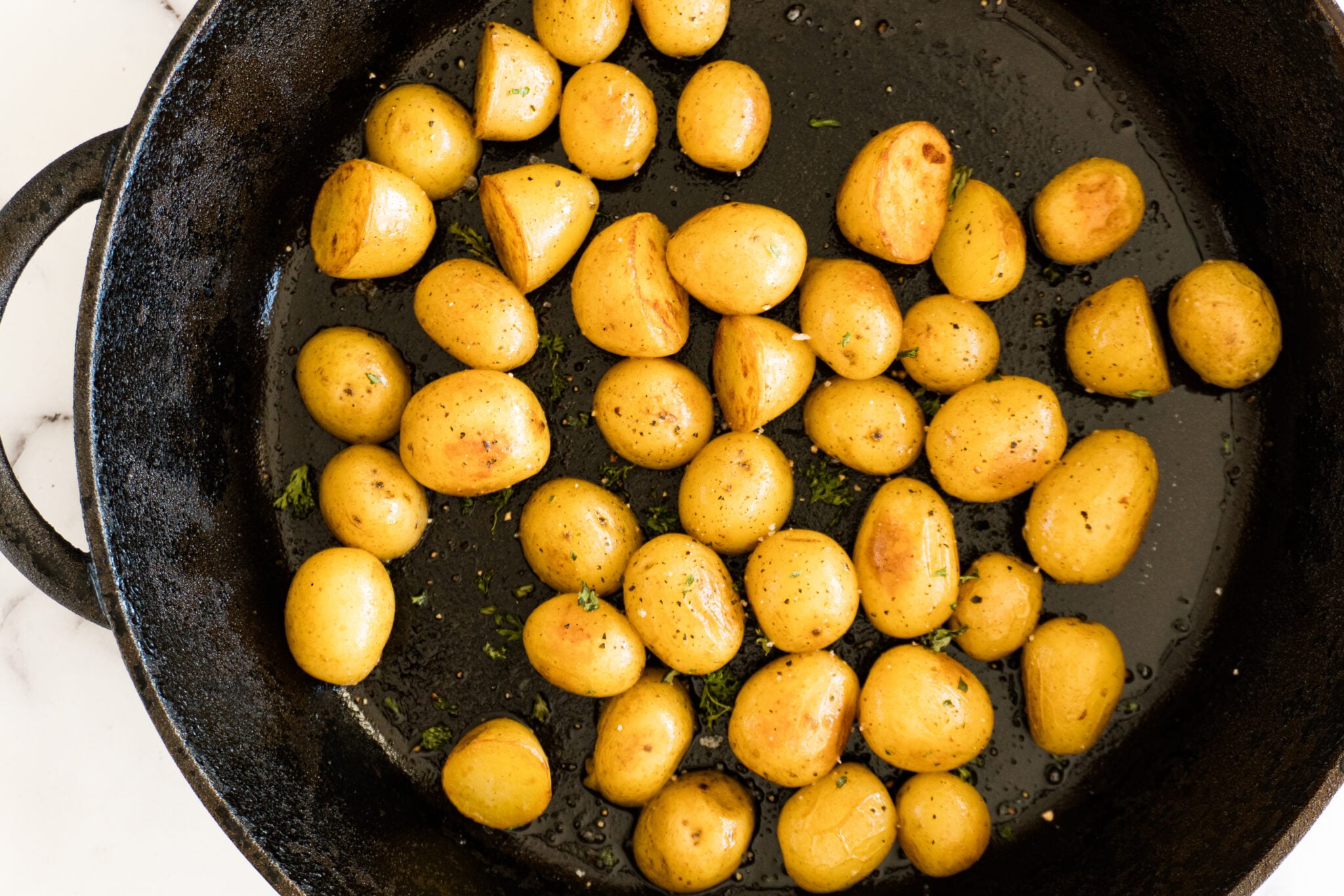 Sous vide potatoes browned and crisp on the edges in a cast iron skillet.