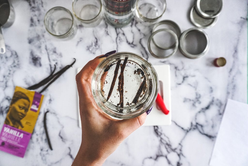 Clear vodka in a mason jar with vanilla beans in it.