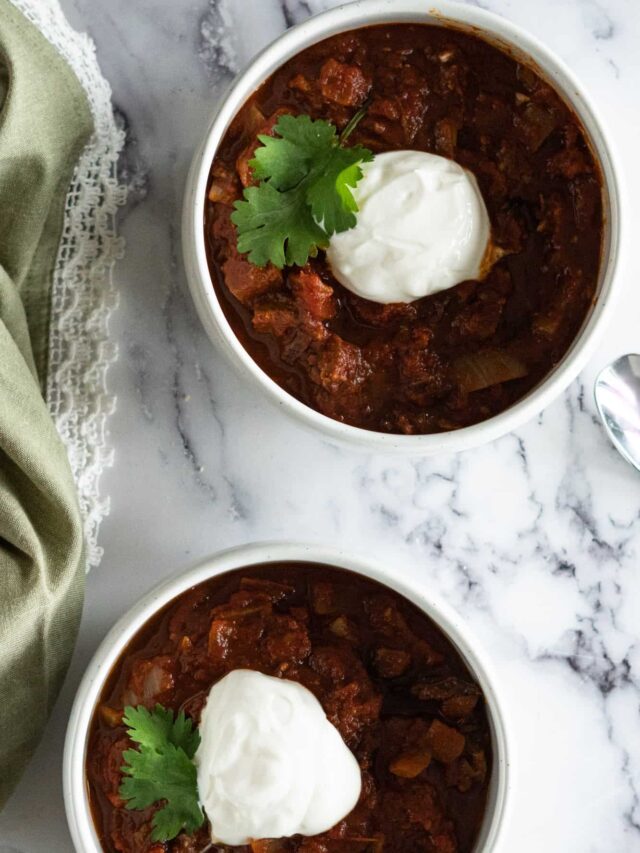 Two bowls with brisket chili and topped with sour cream.
