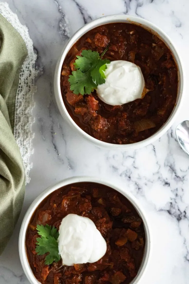 Two bowls with brisket chili and topped with sour cream.