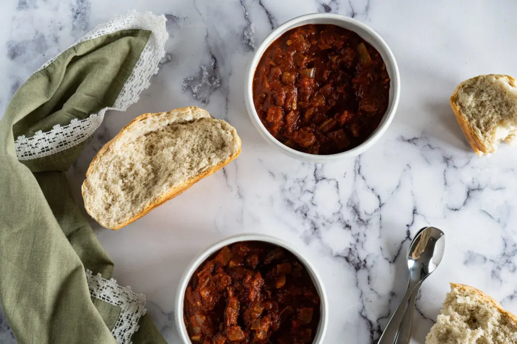 Two bowls of leftover brisket chili with bread.