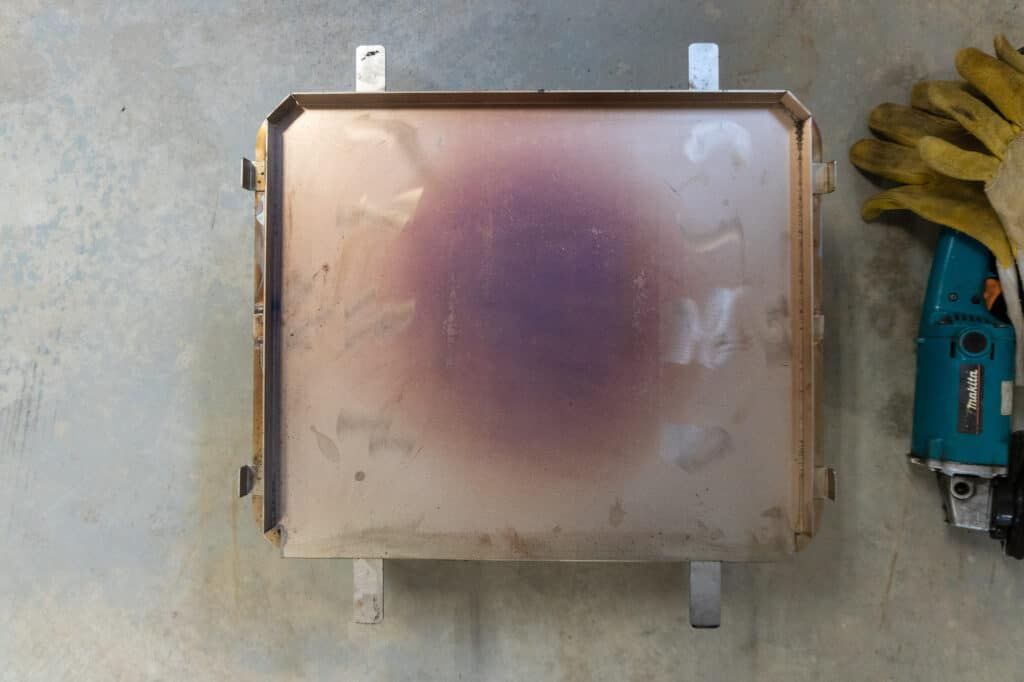 GMG pizza oven sitting on a pot holder on the floor.