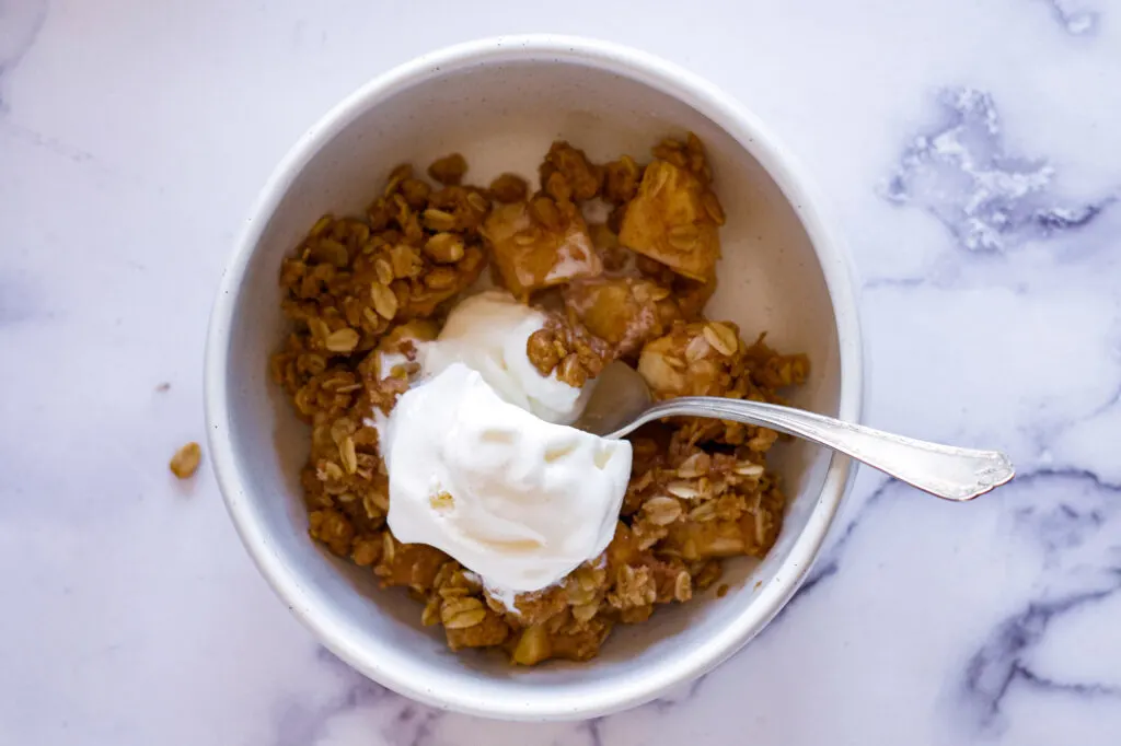 A bowl of apple crisp with ice cream