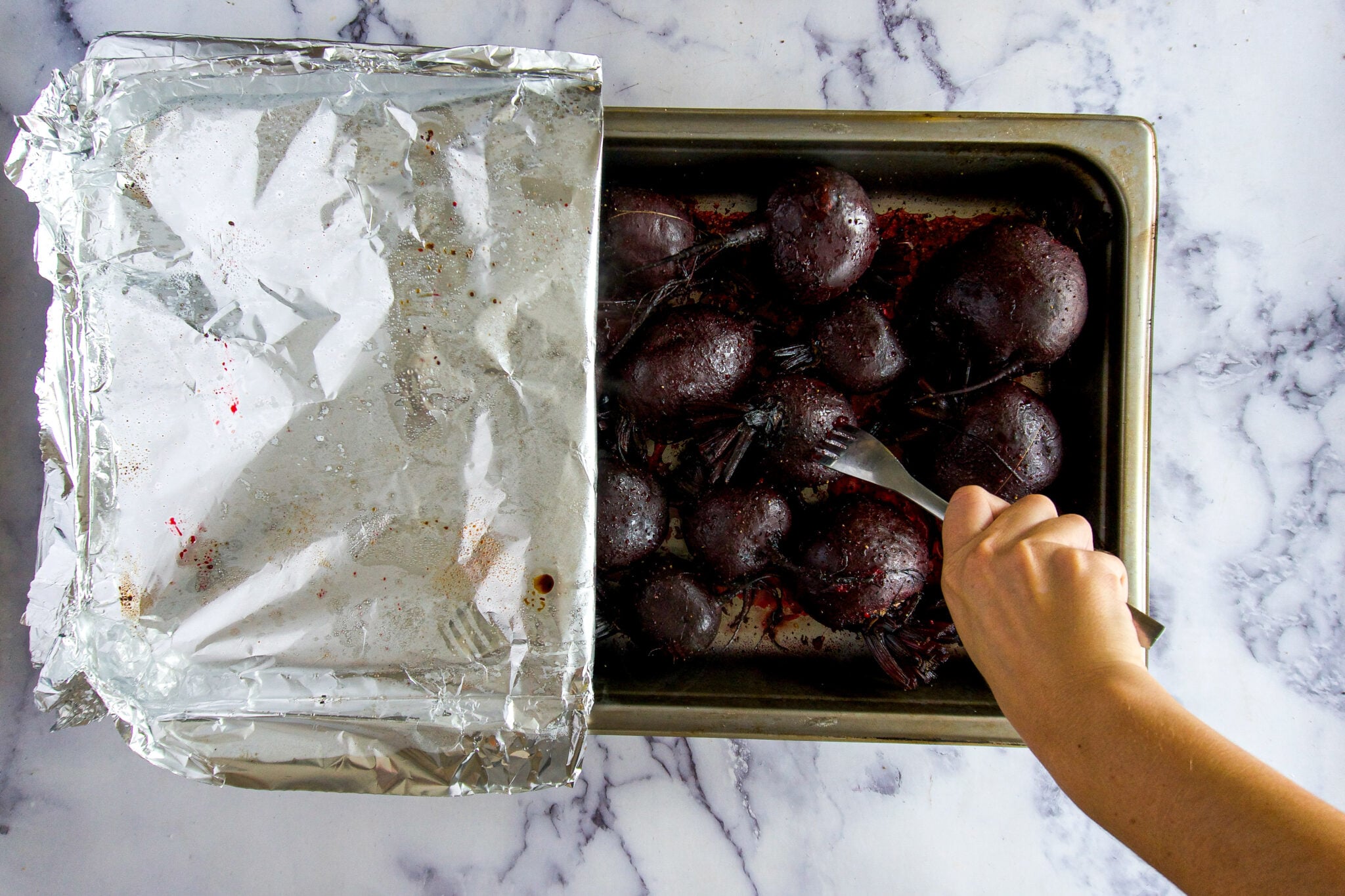 Testing for doneness by piercing roasted beets with a fork. 