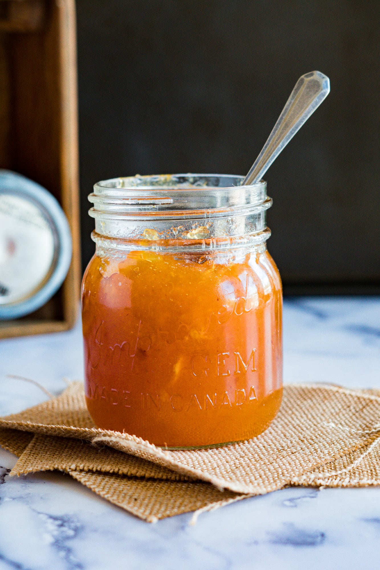 Smoked peach jam in a jar with a spoon sticking out the top.