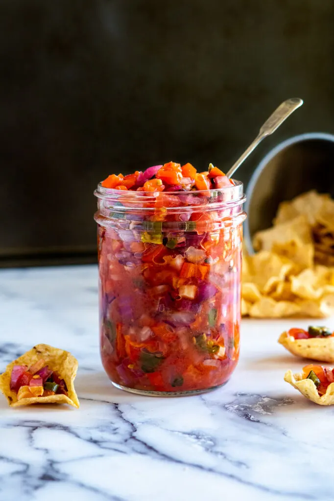 Smoked salsa in a jar surrounded by chips.