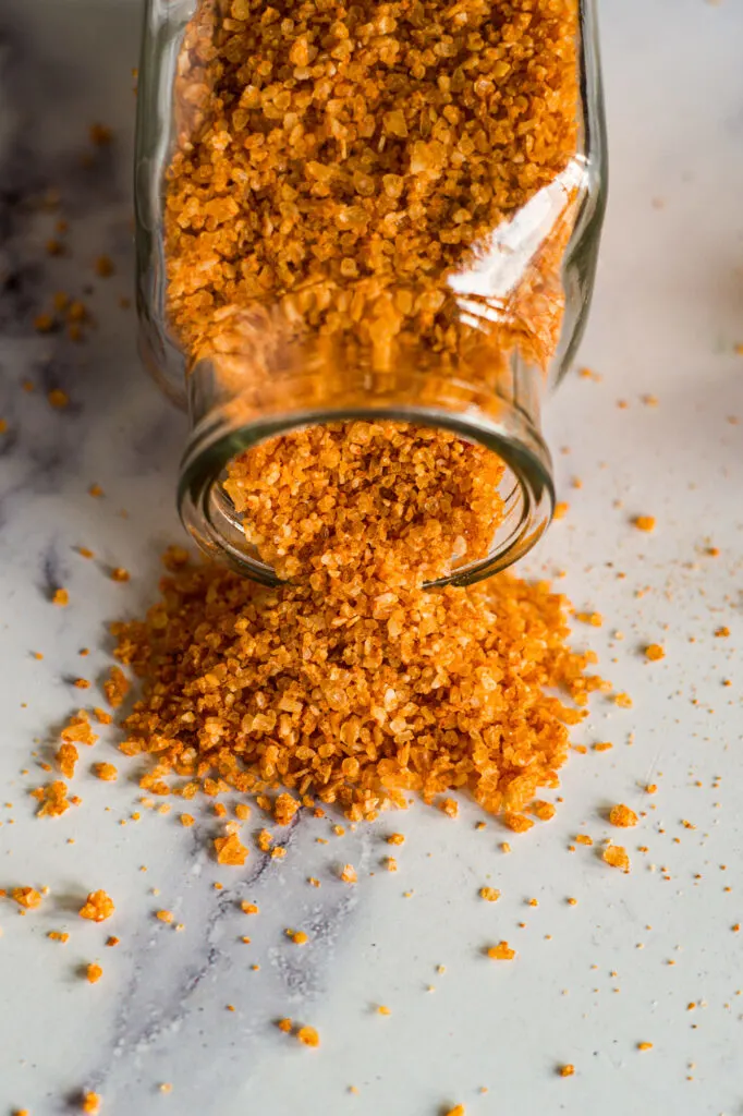 Sriracha salt spilling out of a glass jar.