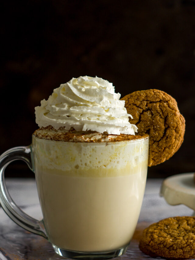 A mug of chai white hot chocolate with a gingersnap garnish.