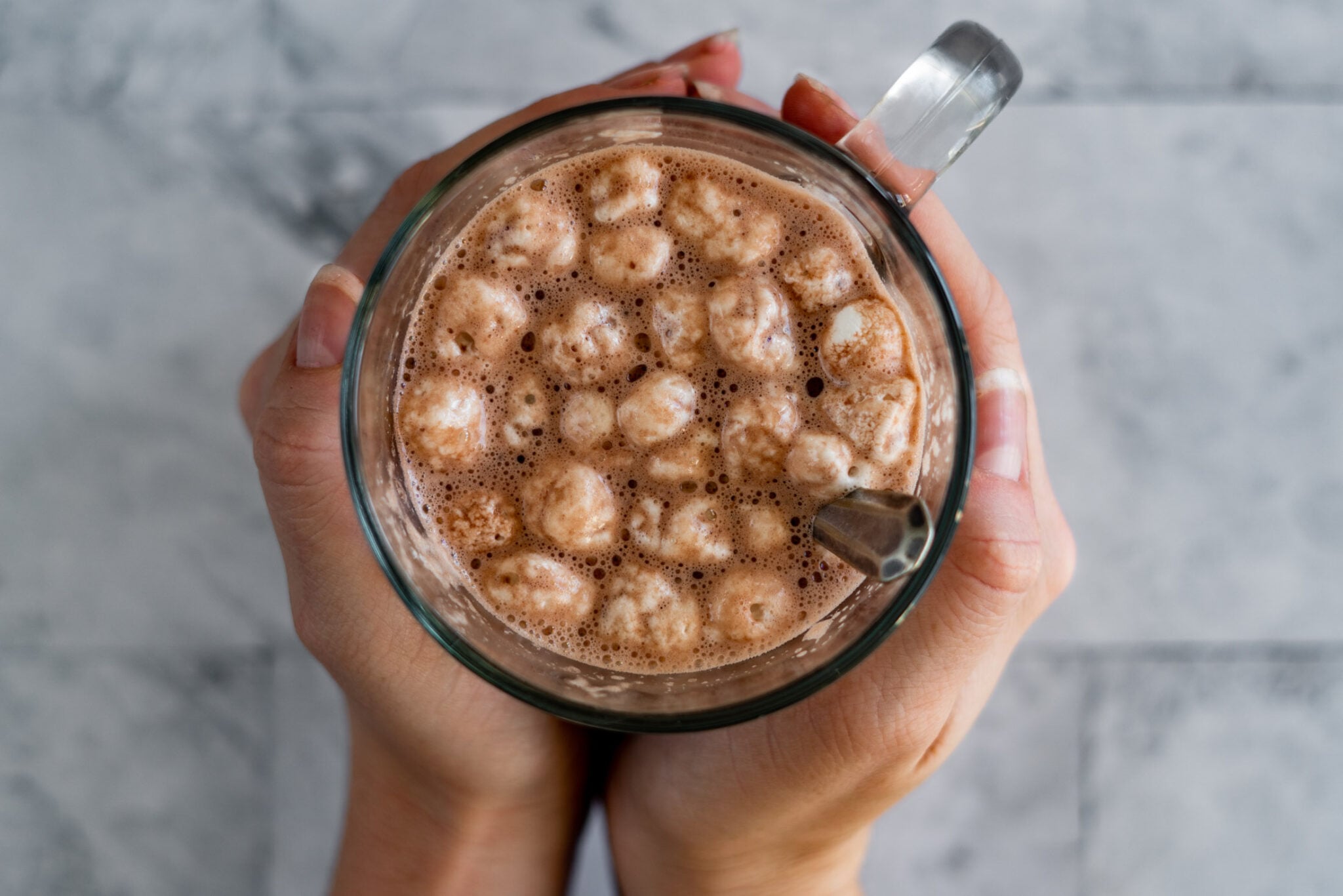 Hands cupping a cup of homemade hot cocoa.
