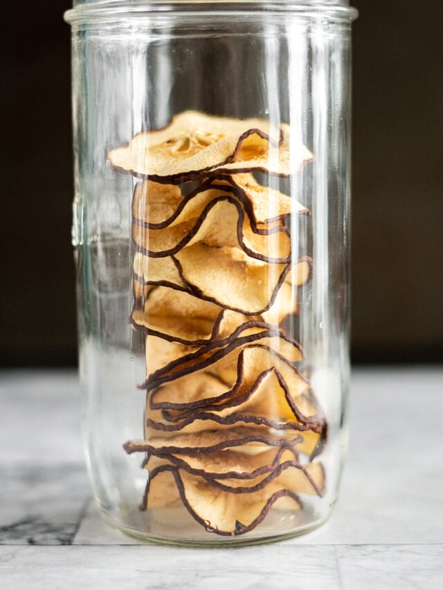 Dried pear slices stacked in a tall mason jar.