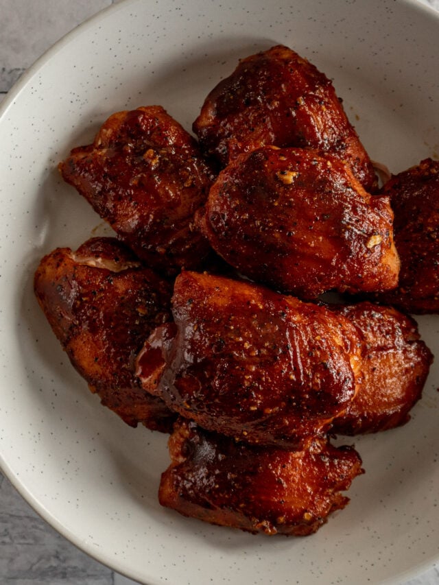 Smoked chicken thighs in a white speckled bowl.