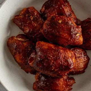 Smoked chicken thighs in a white speckled bowl.