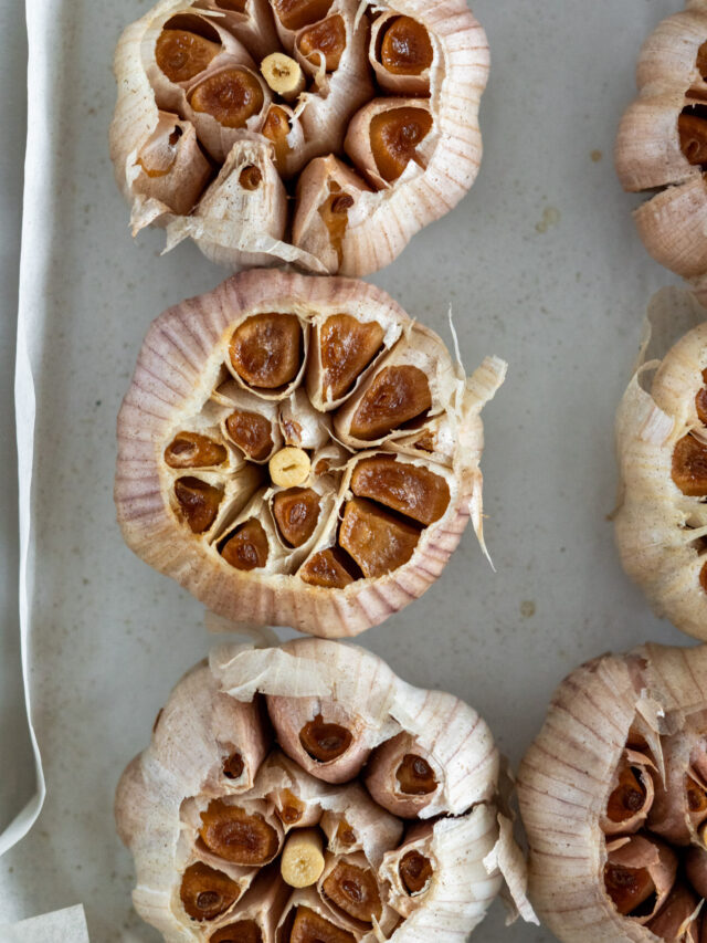 Browned and smoked garlic in a parchment lined sheet pan.