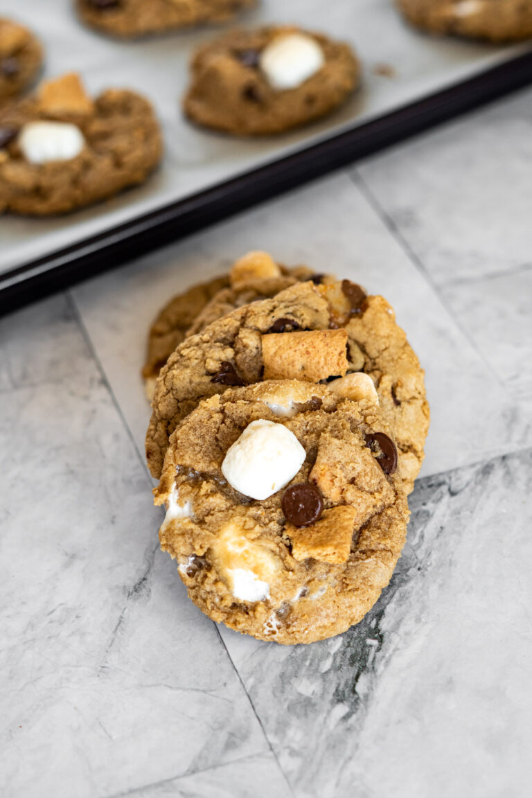 A stack of s'more cookies dotted with marshmallows, chocolate chips and graham crackers.