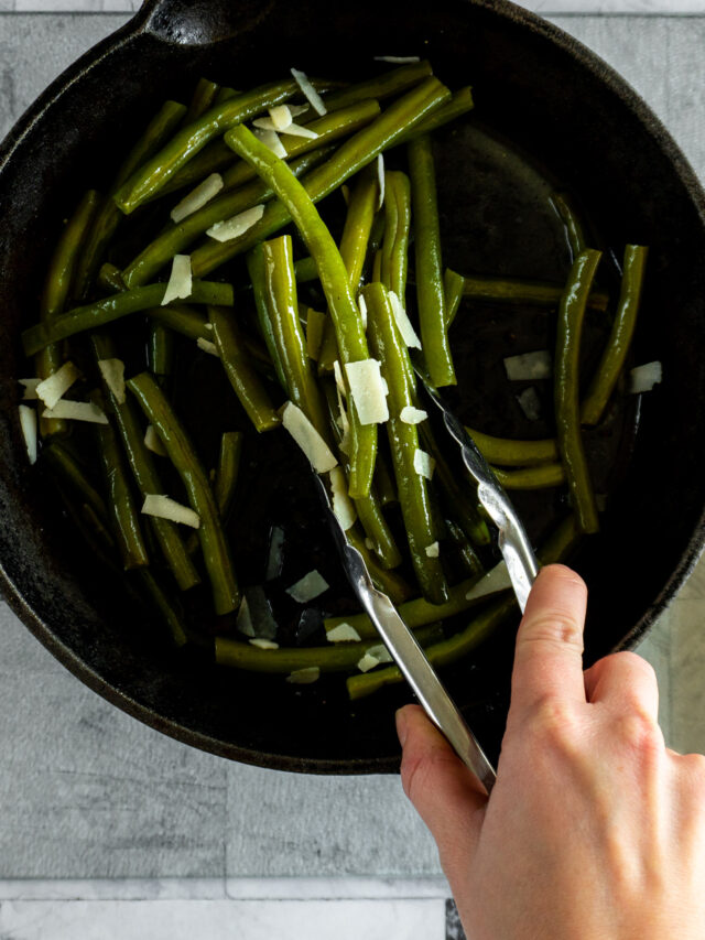 xPicking up the green beans with tongs to move to serving tray.