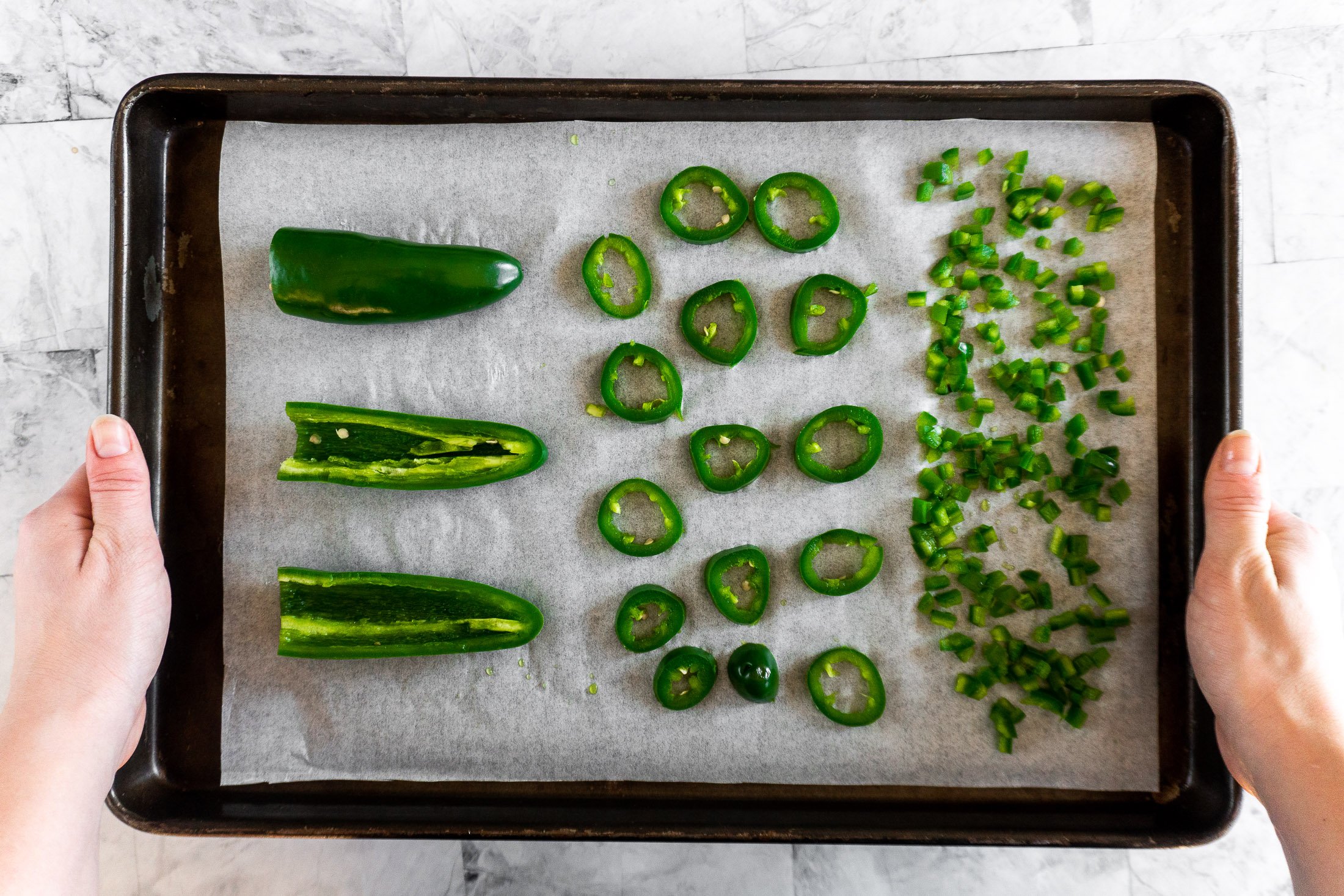 Prepared jalapenos on a baking sheet ready for freezing.
