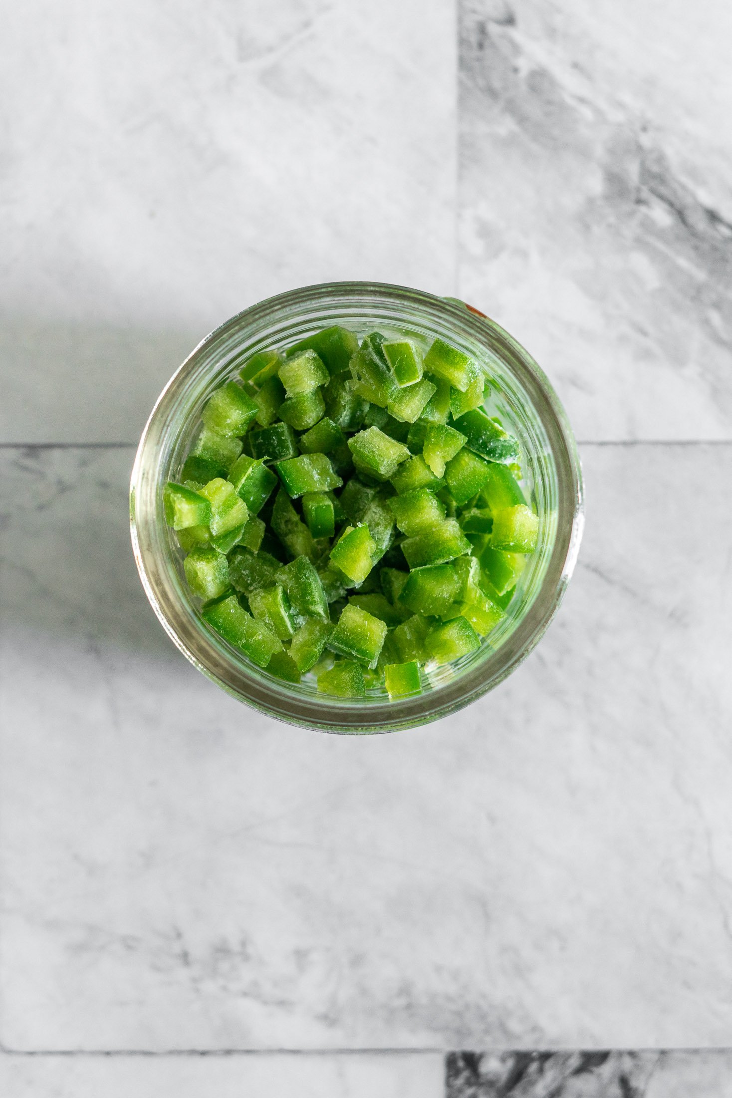 Frozen diced jalapenos in a small mason jar for storage. 