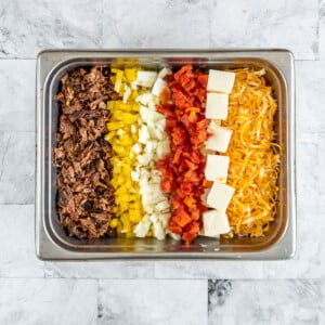 Smoked queso ingredients layered in a chafing pan.