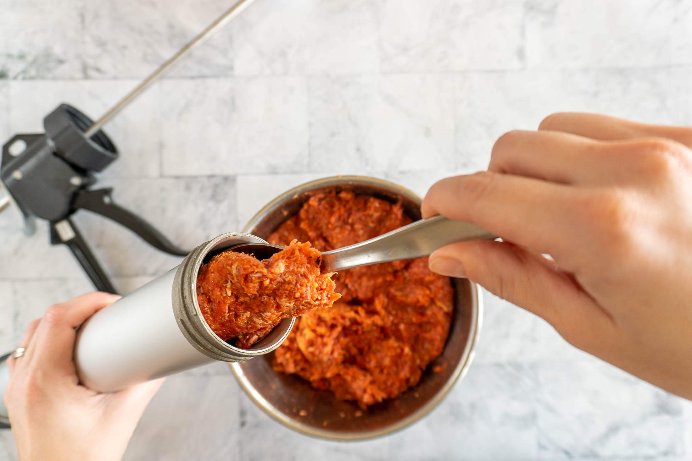 Scooping beef mixture into beef jerky gun.