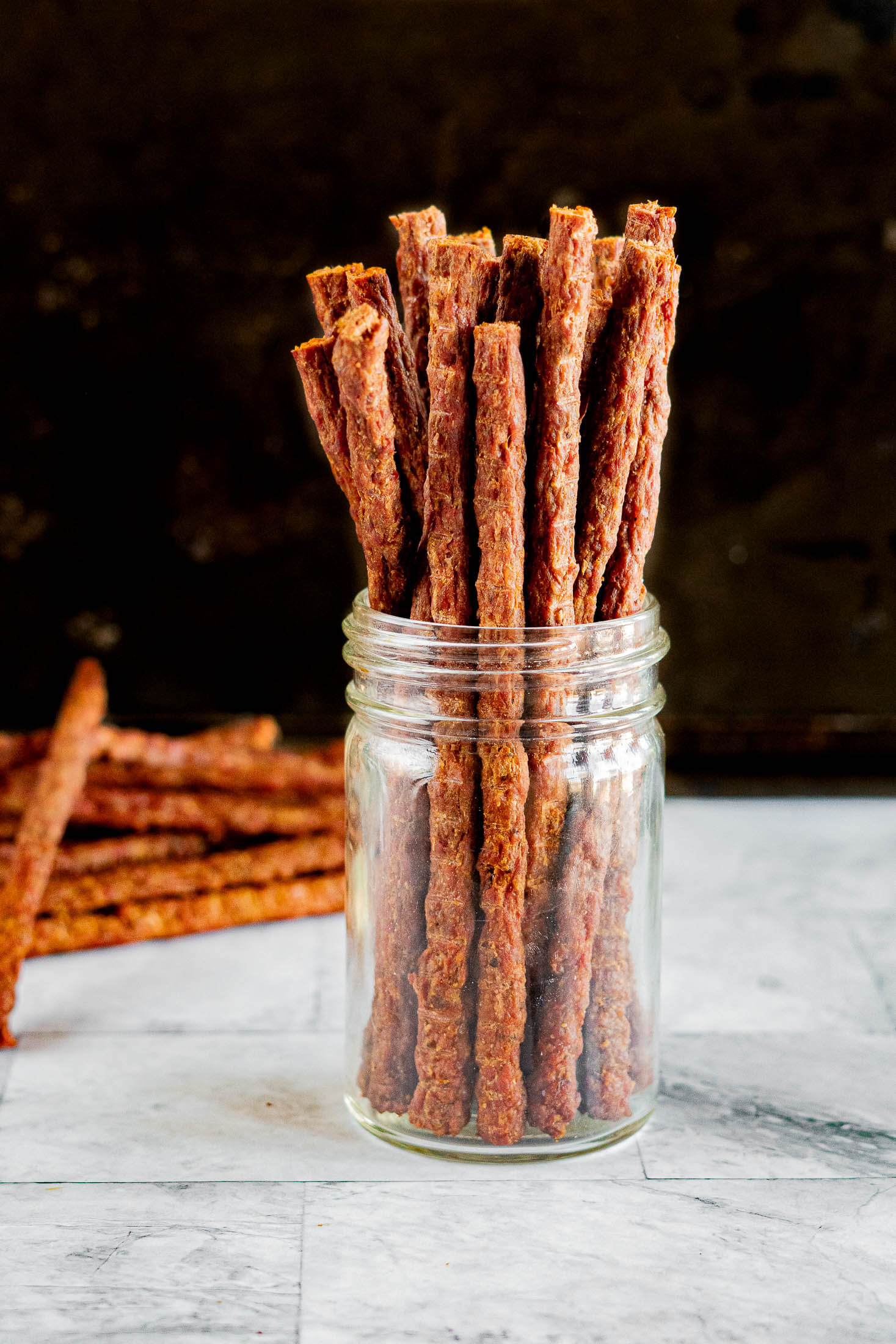 Ground beef jerky sticks in a mason jar.