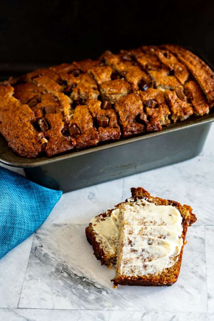 Sliced sourdough banana bread slathered with butter.