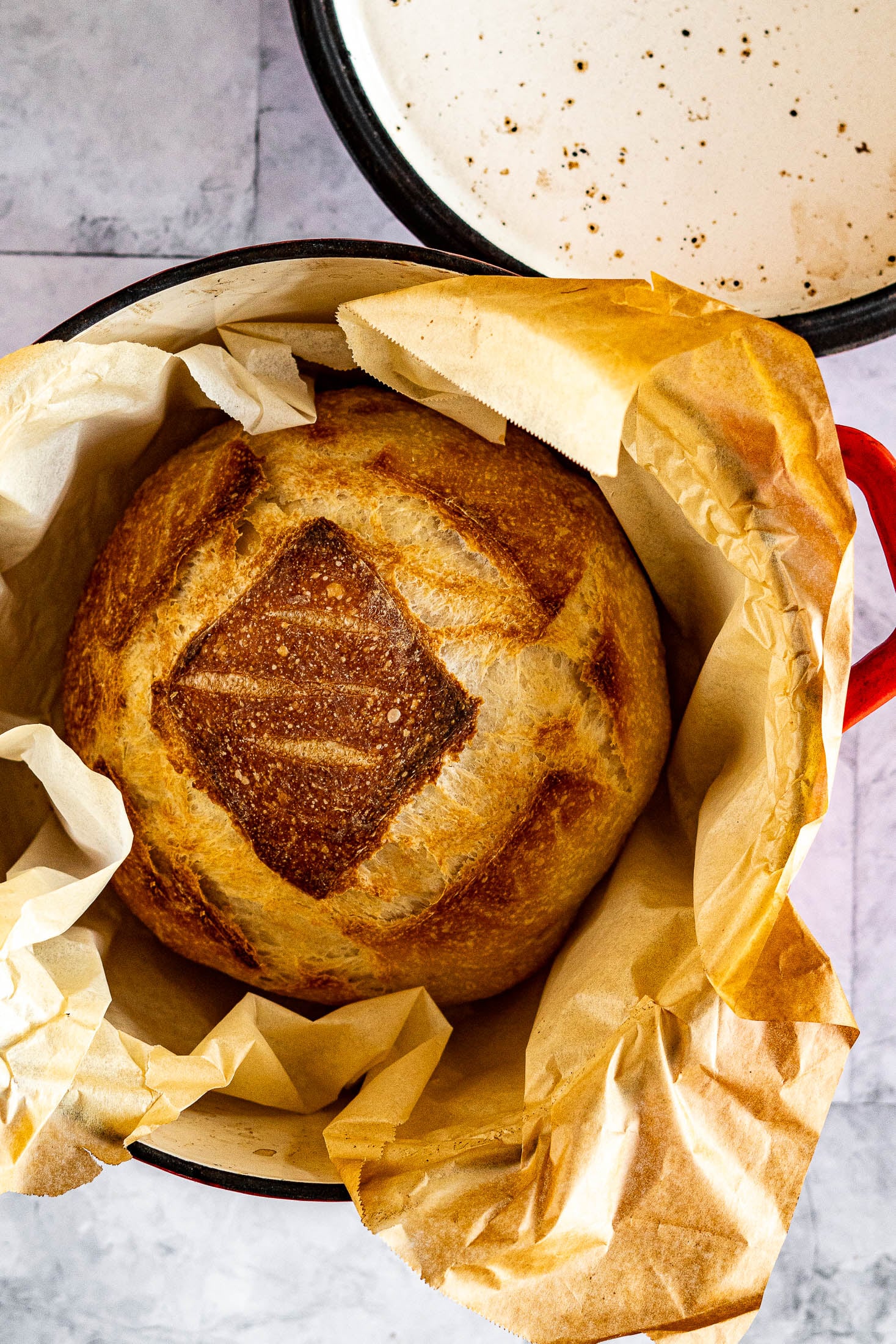 A loaf of sliced sourdough in a red cast iron pot. 