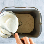 Adding sourdough discard to the bread machine pan.