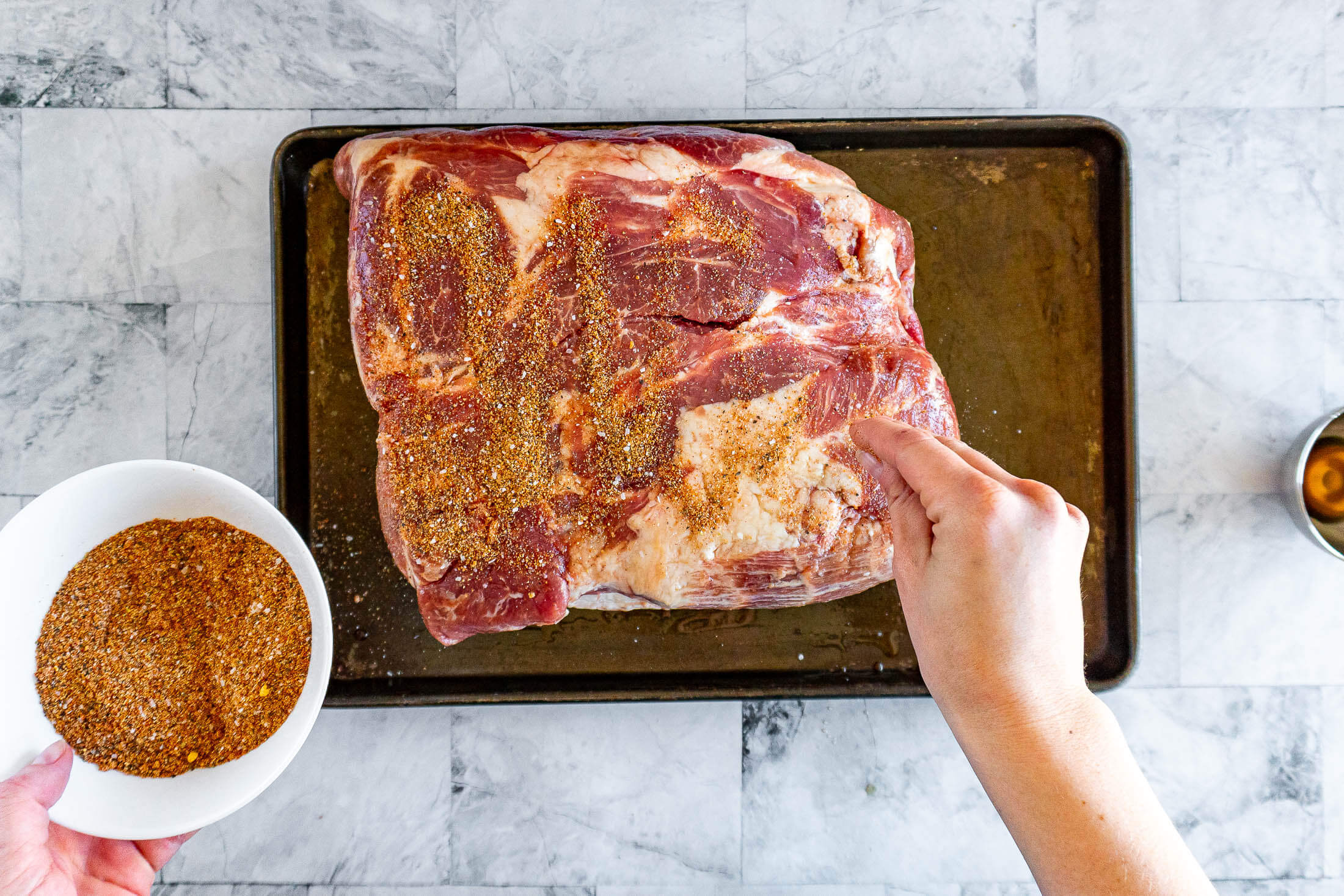 Sprinkling the meat with pork butt dry rub.