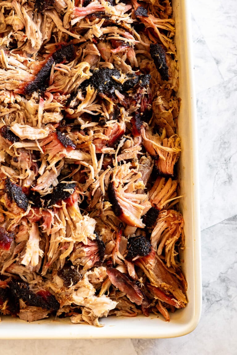 Smoked pulled pork shoulder in a white dish.