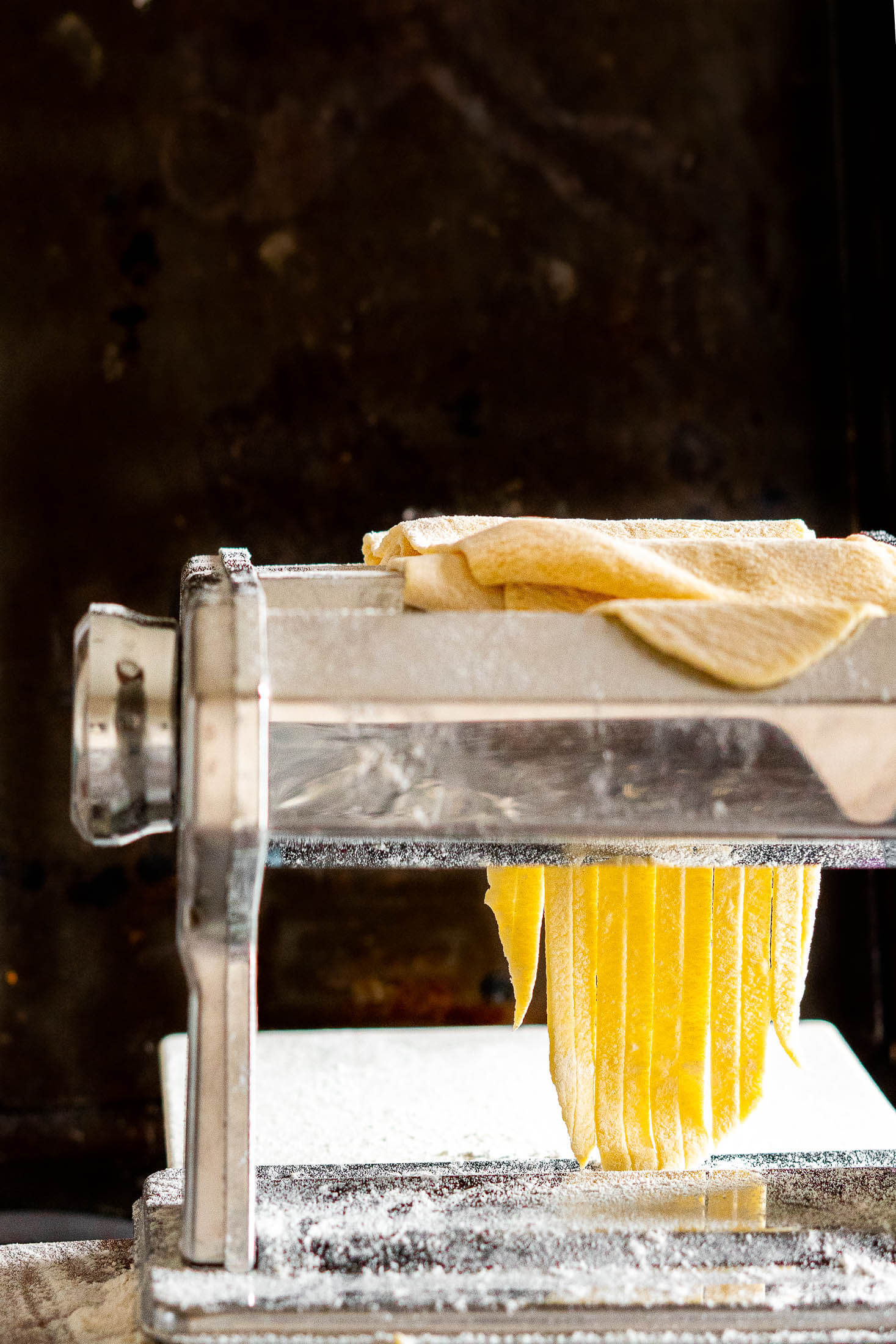 Rolling fresh sourdough pasta through the pasta cutter.