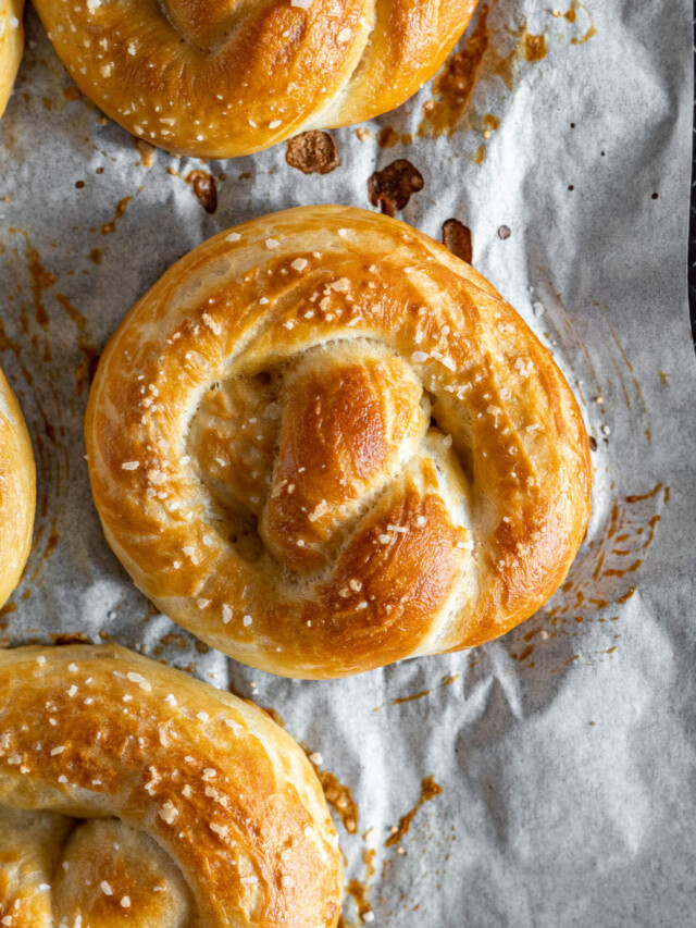 Overhead view of freshly baked sourdough pretzels on a baking sheet.