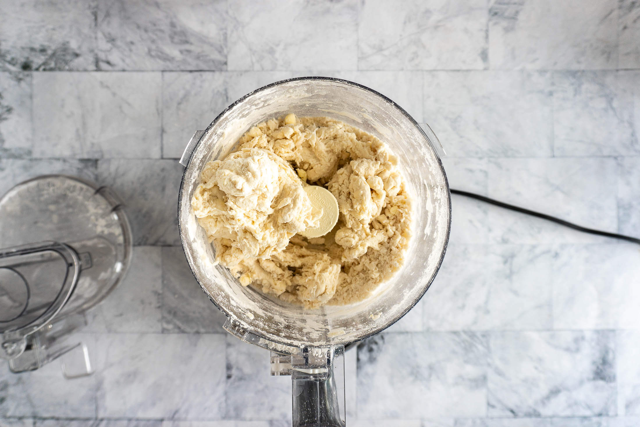 Messy dough in the food processor after pulsing with the water.
